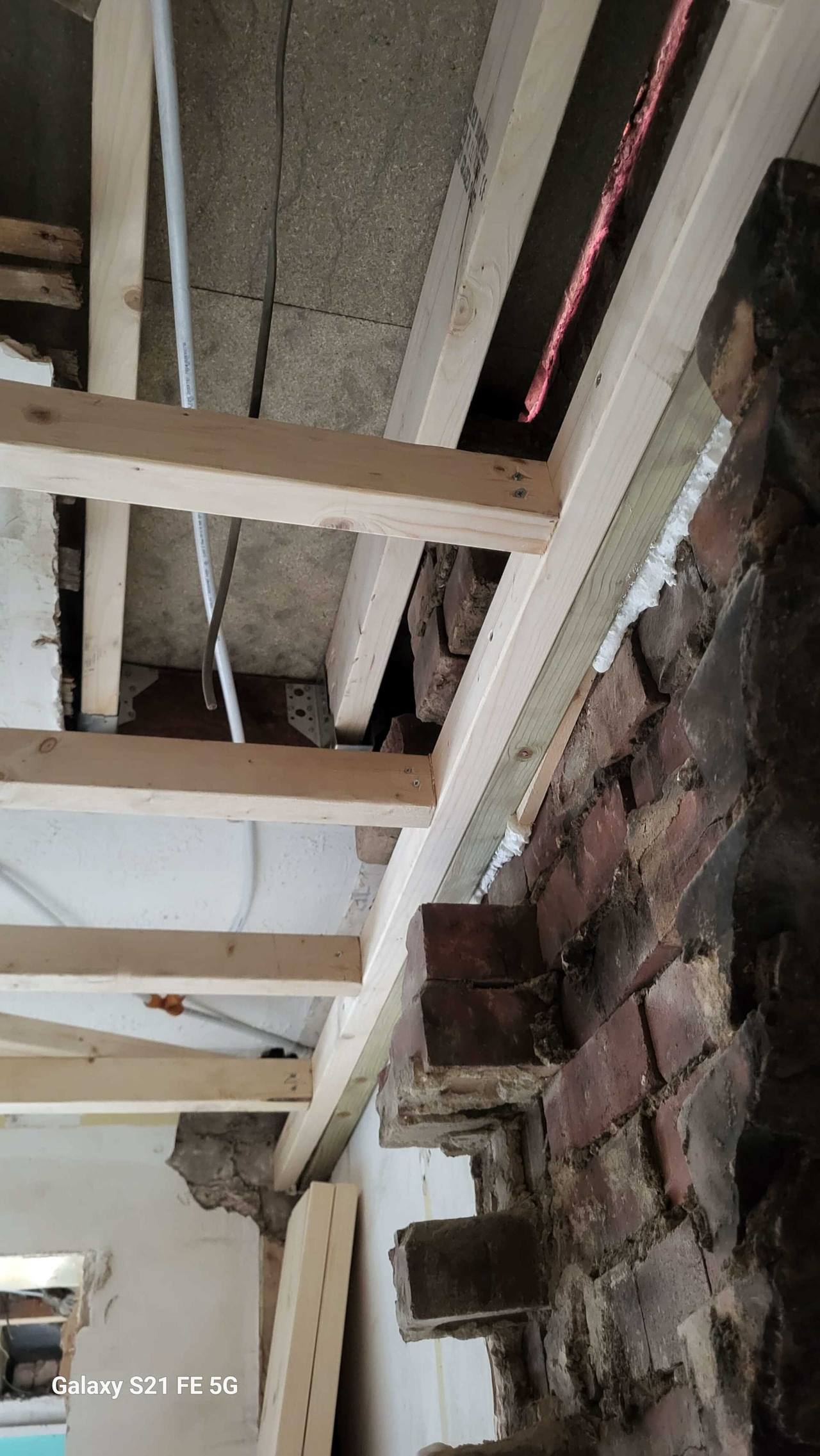 New timber floor joists fixed alongside an exposed brick chimney breast during structural works