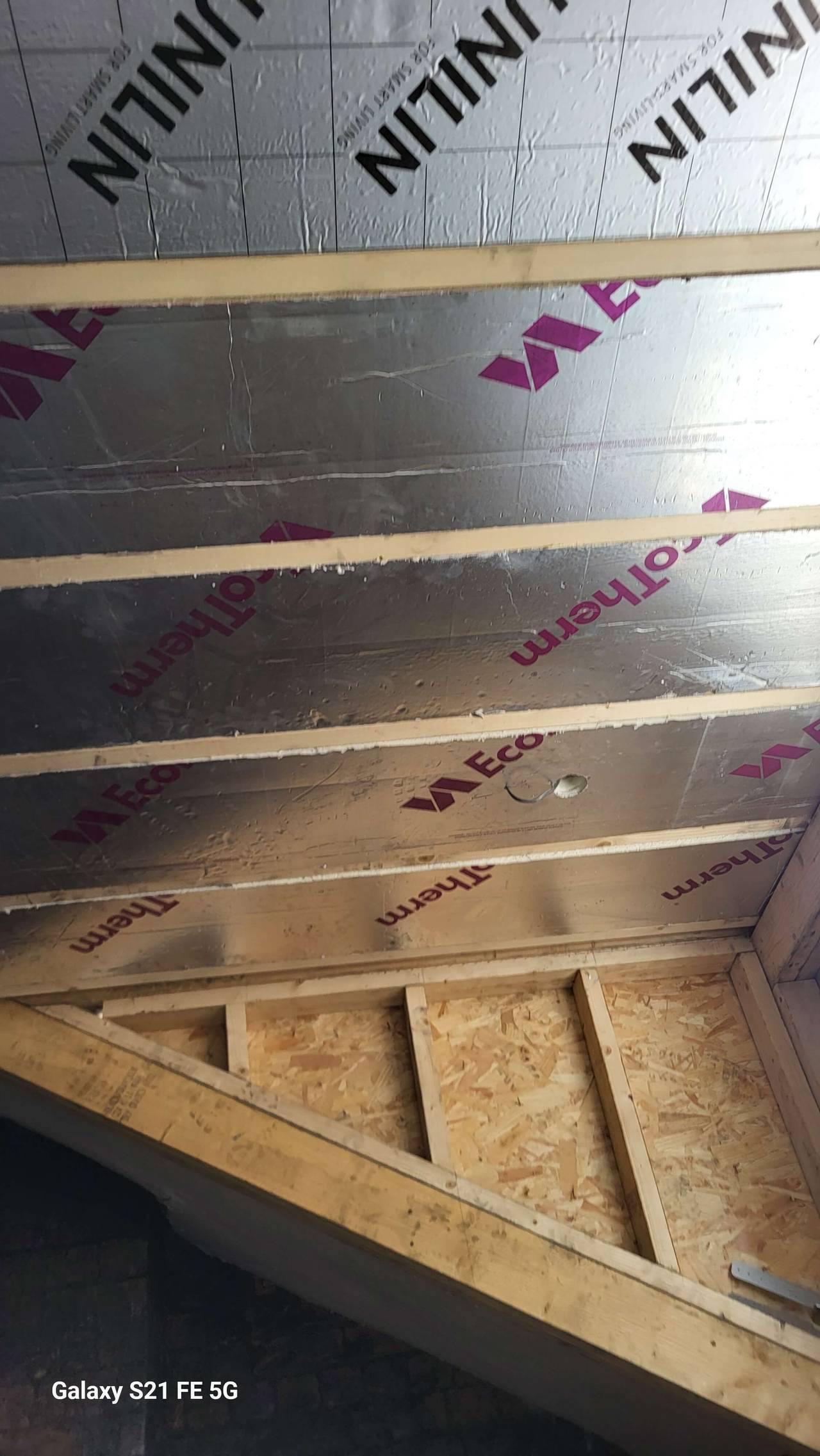 Foil-backed insulation boards fitted between roof rafters above a timber knee-wall frame