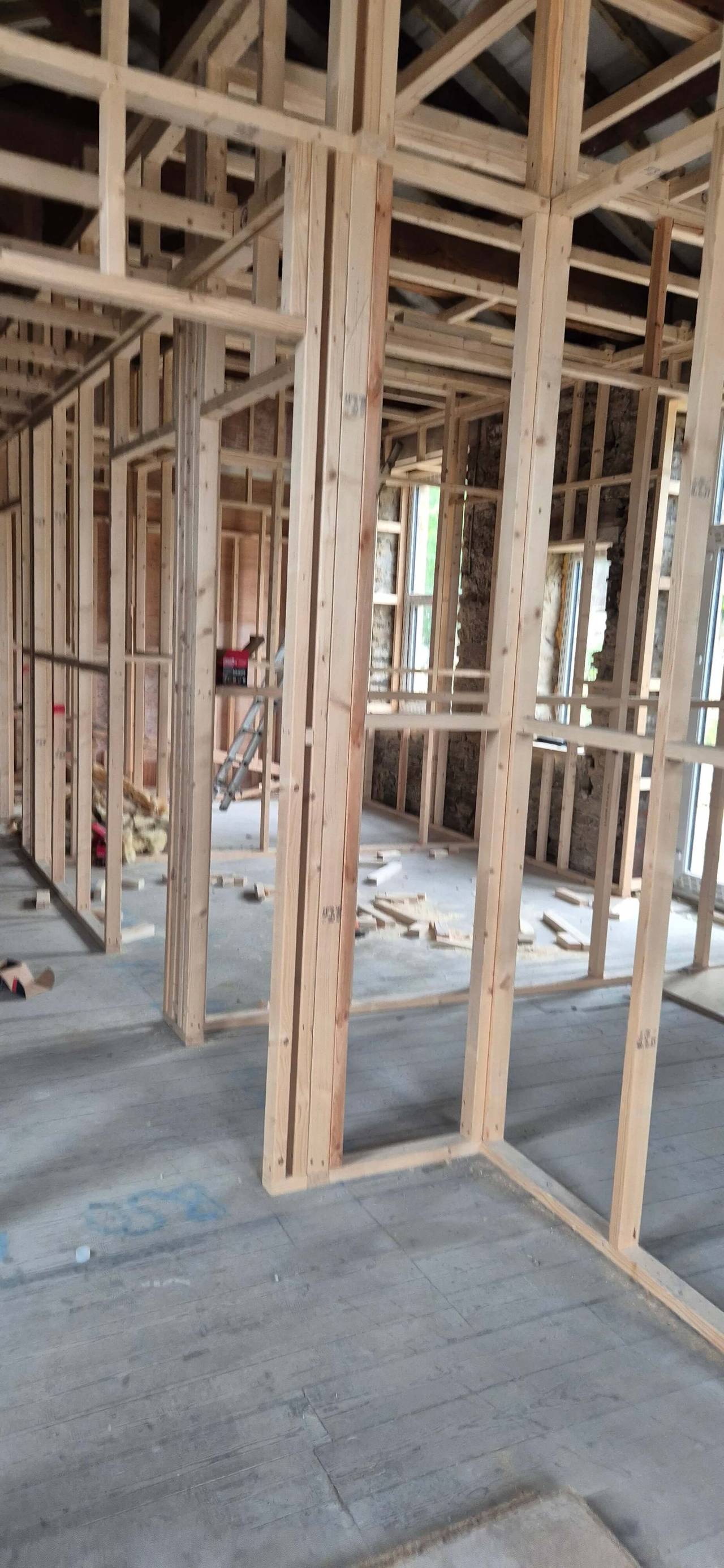 Timber stud partitions framing out new rooms inside a stripped-back building, with roof timbers overhead