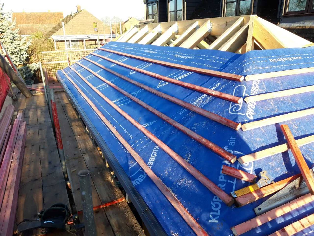 Pitched extension roof covered in blue breathable membrane with red tile battens fixed, ready for tiling
