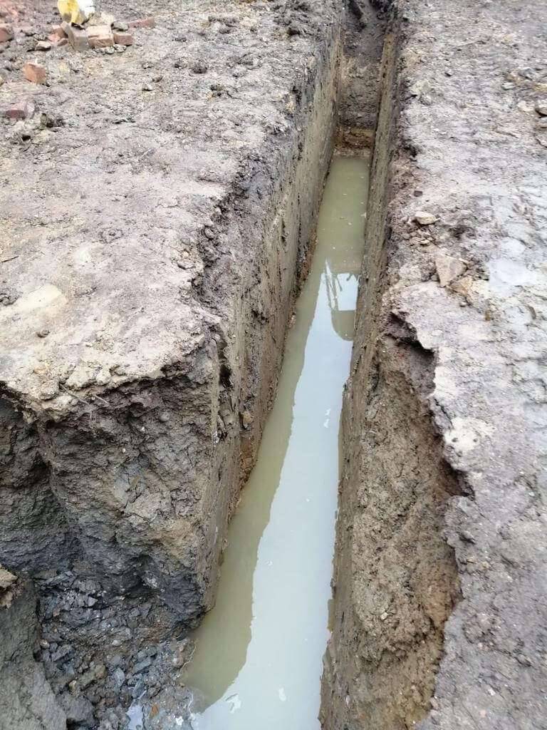 Freshly dug foundation trench partly filled with groundwater on a building site