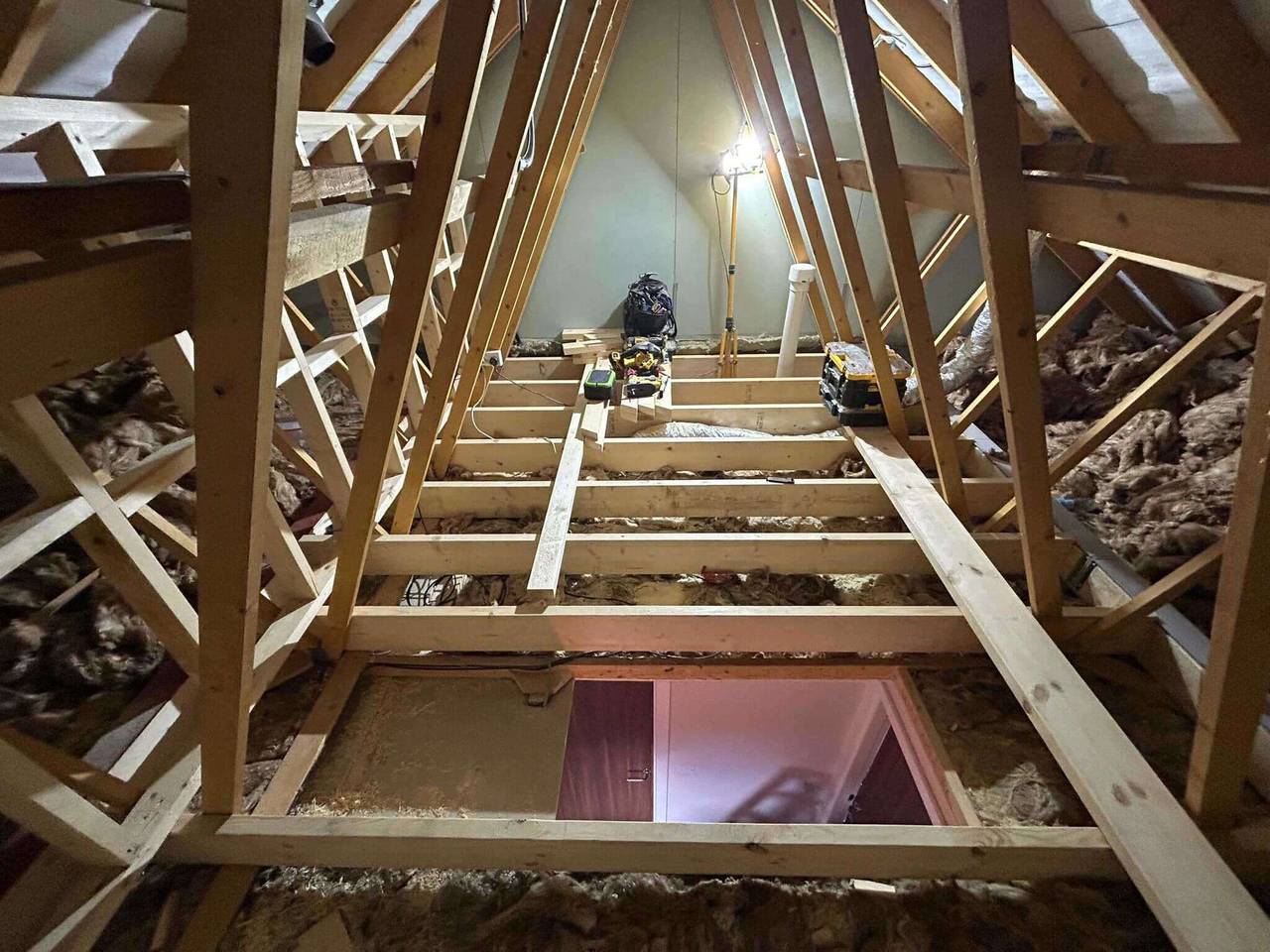 Loft space with new floor joists and structural timbers fitted between the existing roof trusses at the start of a loft conversion