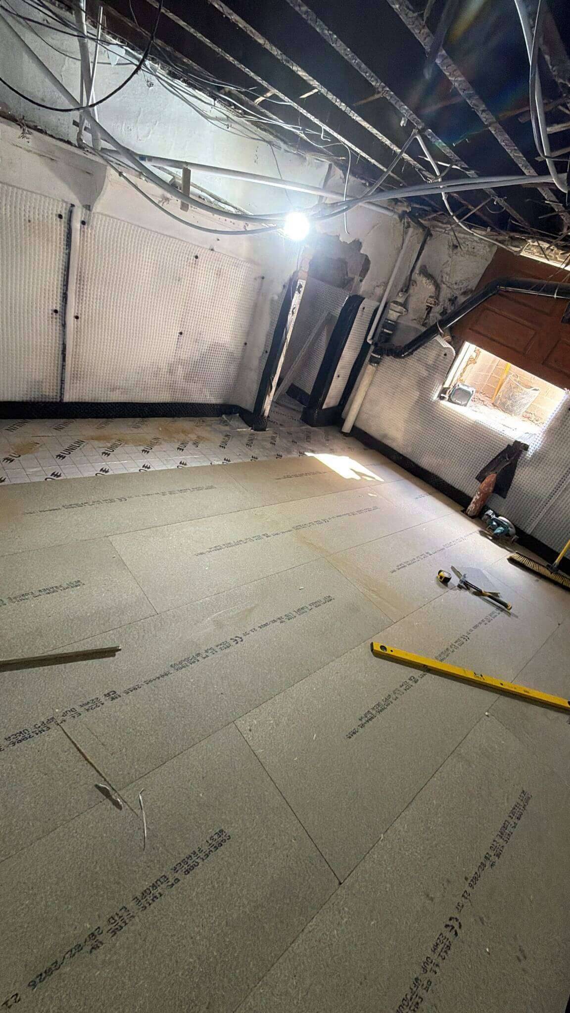 Basement room with a new chipboard floor laid over insulation and cavity drainage membrane lining the walls