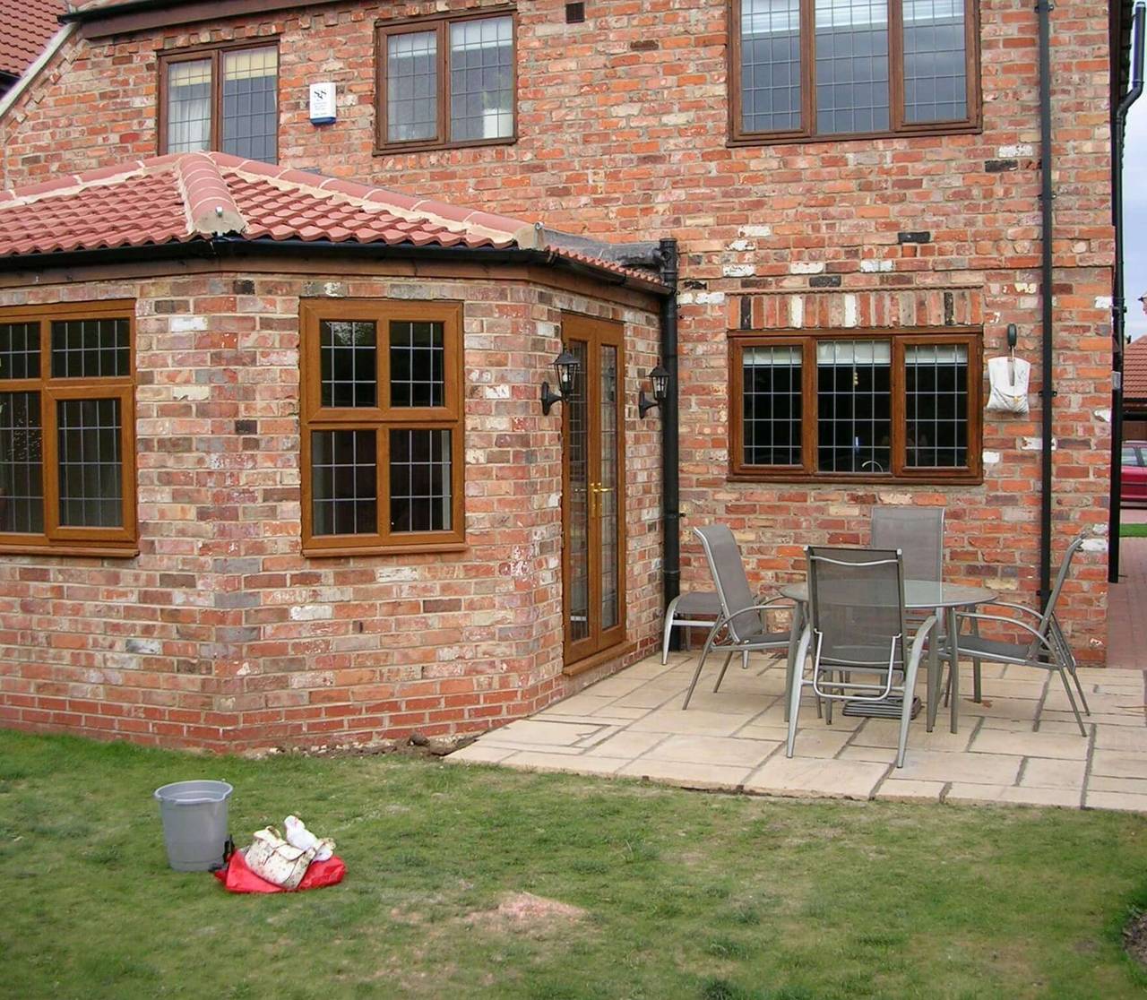 Completed single-storey brick extension with a terracotta tiled roof, leaded oak-effect windows and French doors opening onto a paved patio