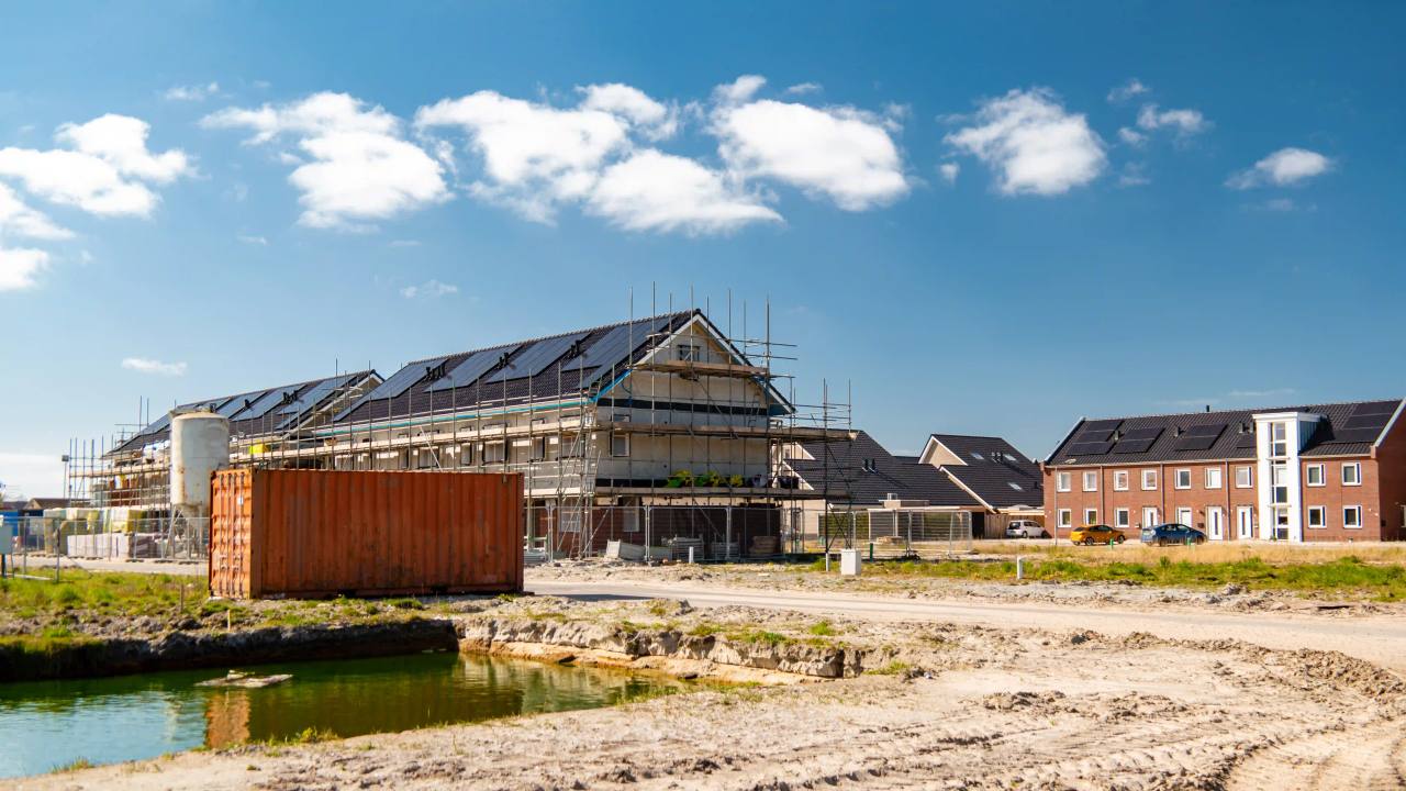 New homes with solar panels under construction behind scaffolding on a residential development