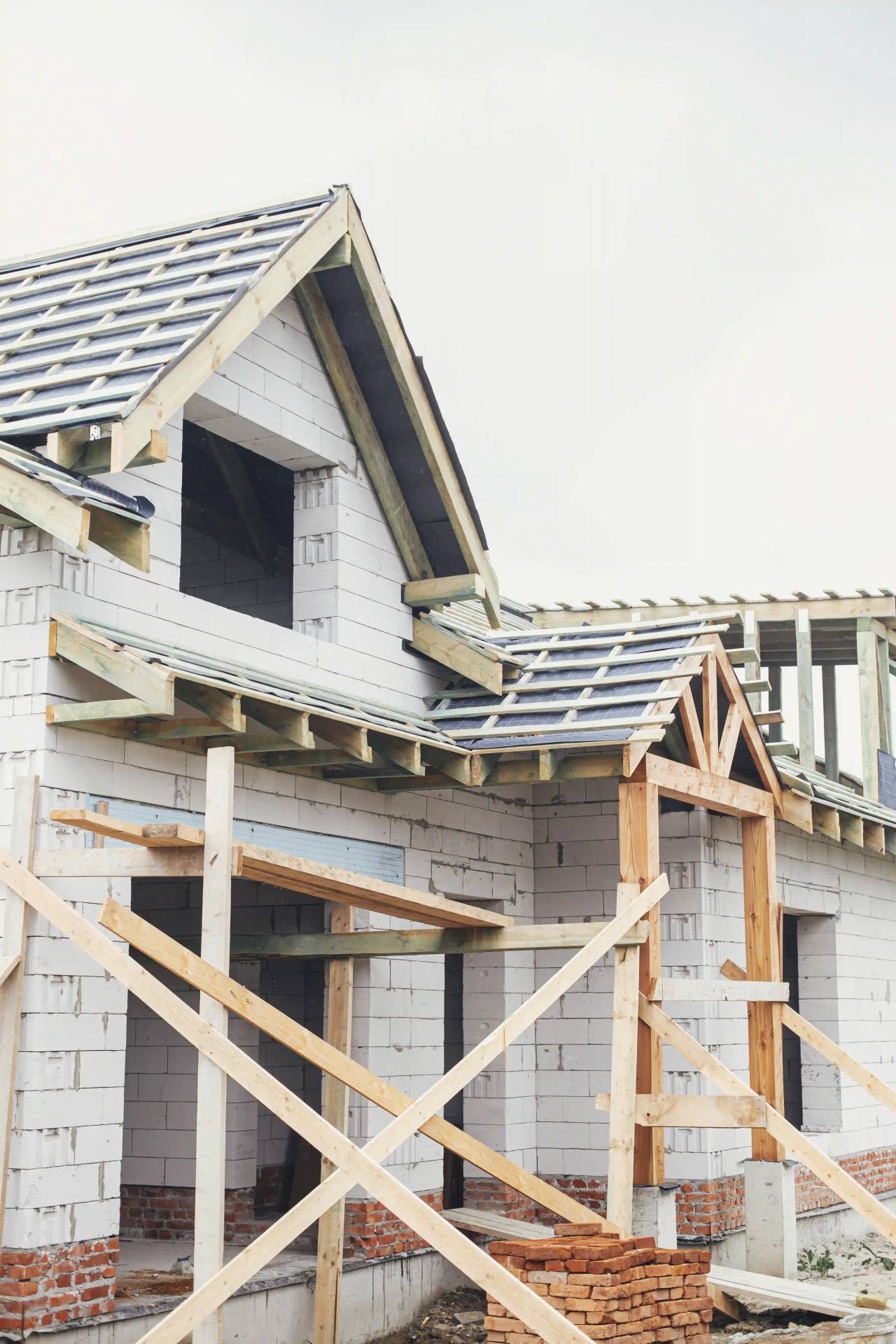 New house in white blockwork with its timber roof structure and battens in place during construction